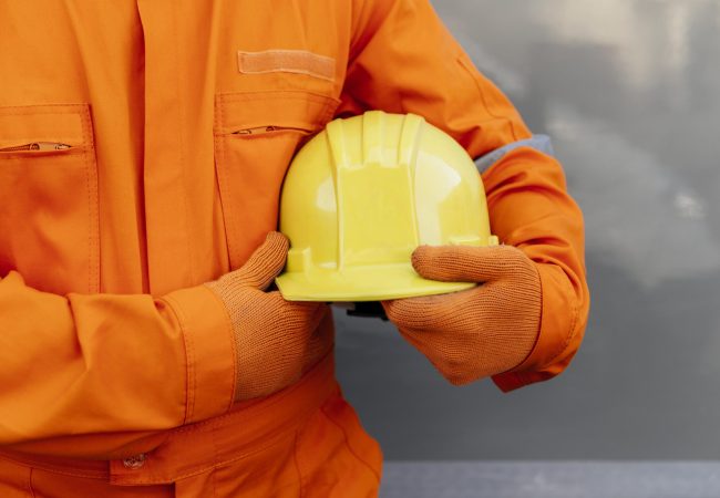 vista-frontal-trabalhador-de-uniforme-segurando-capacete